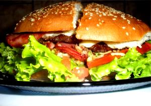 Quantas calorias em 1 Porção Sanduíche hambúrguer com alface tomate queijo prato bacon maionese e ovo frito?