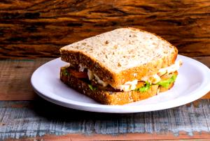 Quantas calorias em 1 Porção Sanduíche peito de frango grelhado (pão de hambúrguer) com queijo prato cebola e pepino?